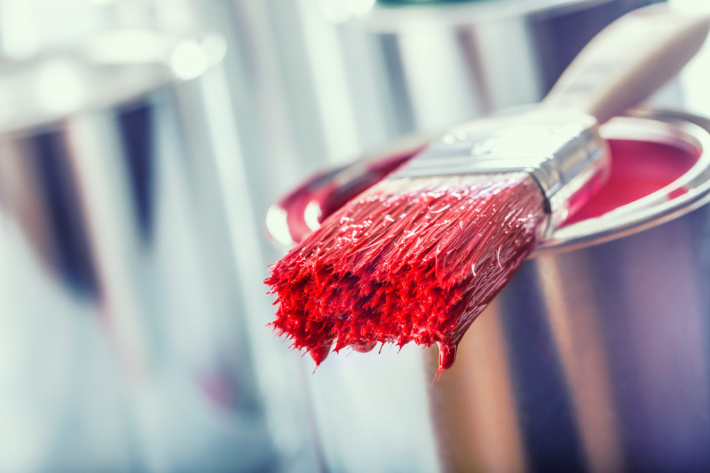 Paint brush splattered in red paint.