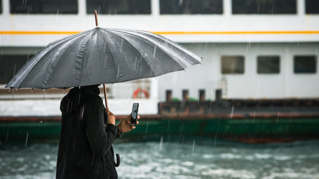 Person using their smartphone in the rain.